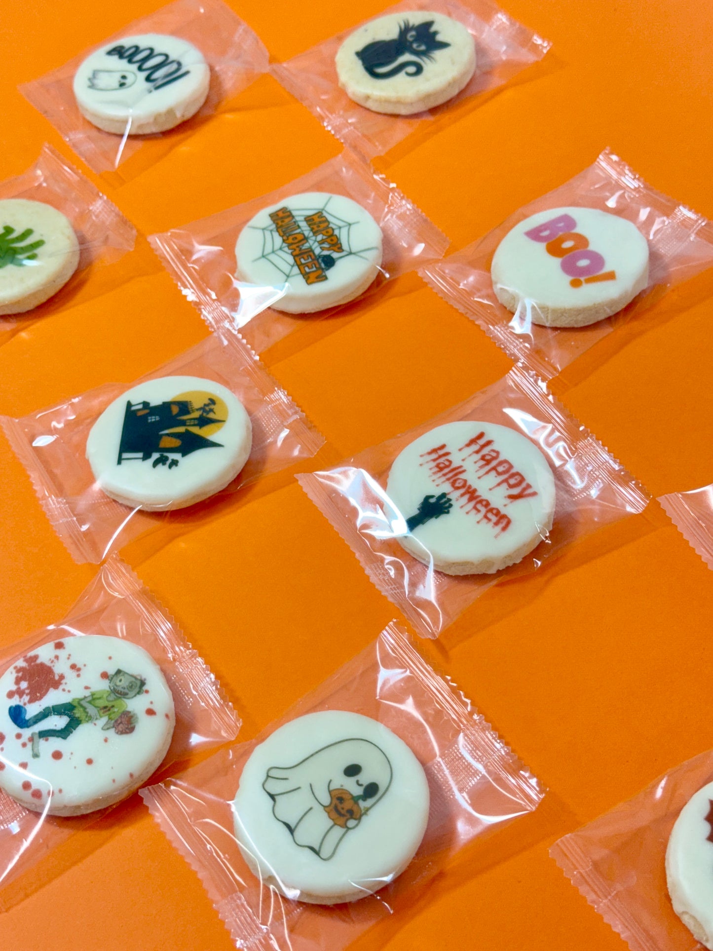 Halloween-themed cookies in clear packaging on an orange background
