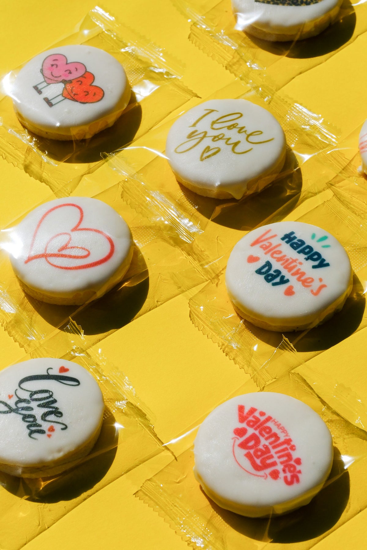 Decorative cookies with Valentine's Day messages on a yellow surface